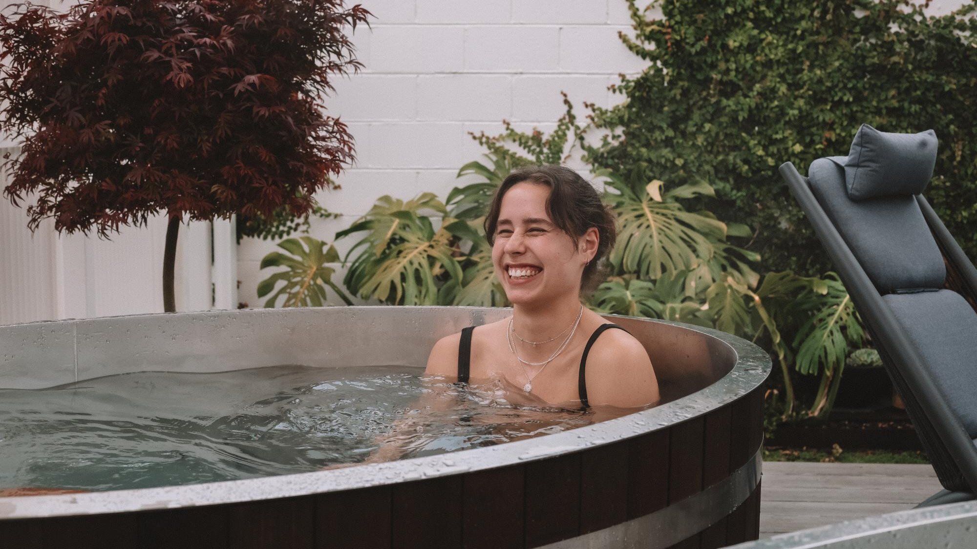 A smiling happy woman enjoying the coldness of a hot and cold water immersion therapy in Wildsoul Wellness in Mordialloc, Melbourne.